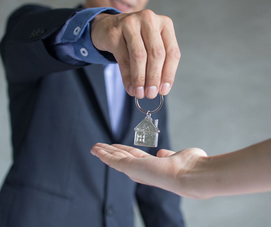 Real estsate agent handing keys to a home buyer.